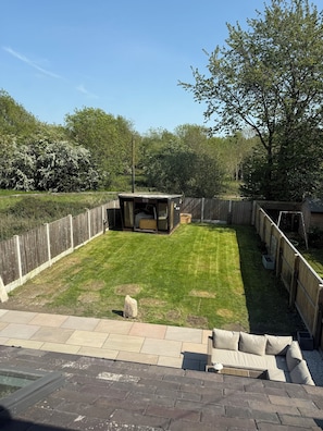 A backyard with a fenced area, a small shed, a lawn, and a patio with outdoor furniture.