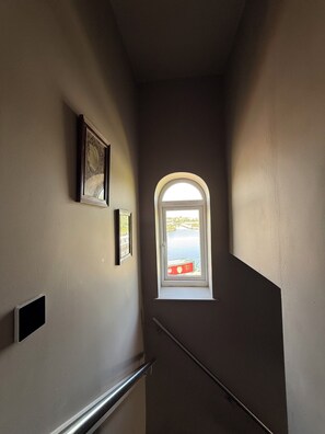 A stairwell with a window at the top, a door, and a wall-mounted light switch.