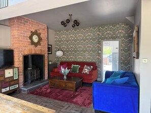 Ein Wohnzimmer mit Kamin aus Ziegelsteinen, einem roten Sofa, einem blauen Sofa und einem Holztisch.