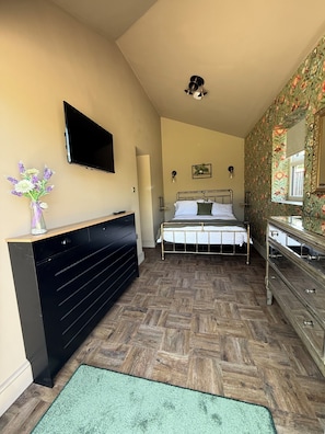 Ein Schlafzimmer mit Bett, Schminktischchen, Kommode und Fernseher.