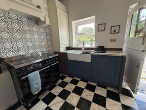 A kitchen with a patterned backsplash, a black and white checkered floor, and a window with a view of greenery.
