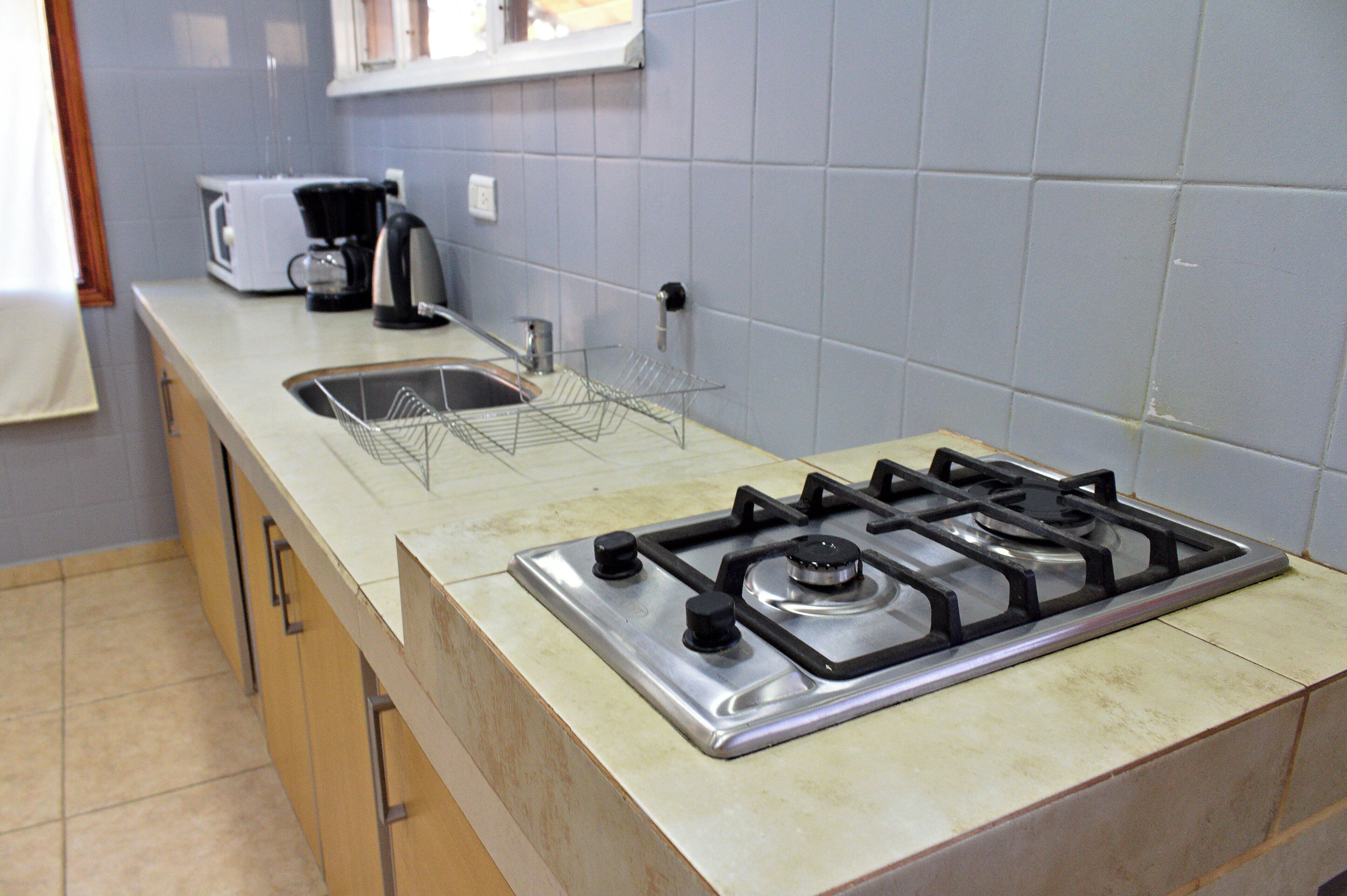 Een keuken met een gasfornuis, een koffiezetapparaat en een spoelbak.