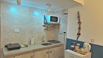 A compact kitchen with a microwave, sink, and countertop.