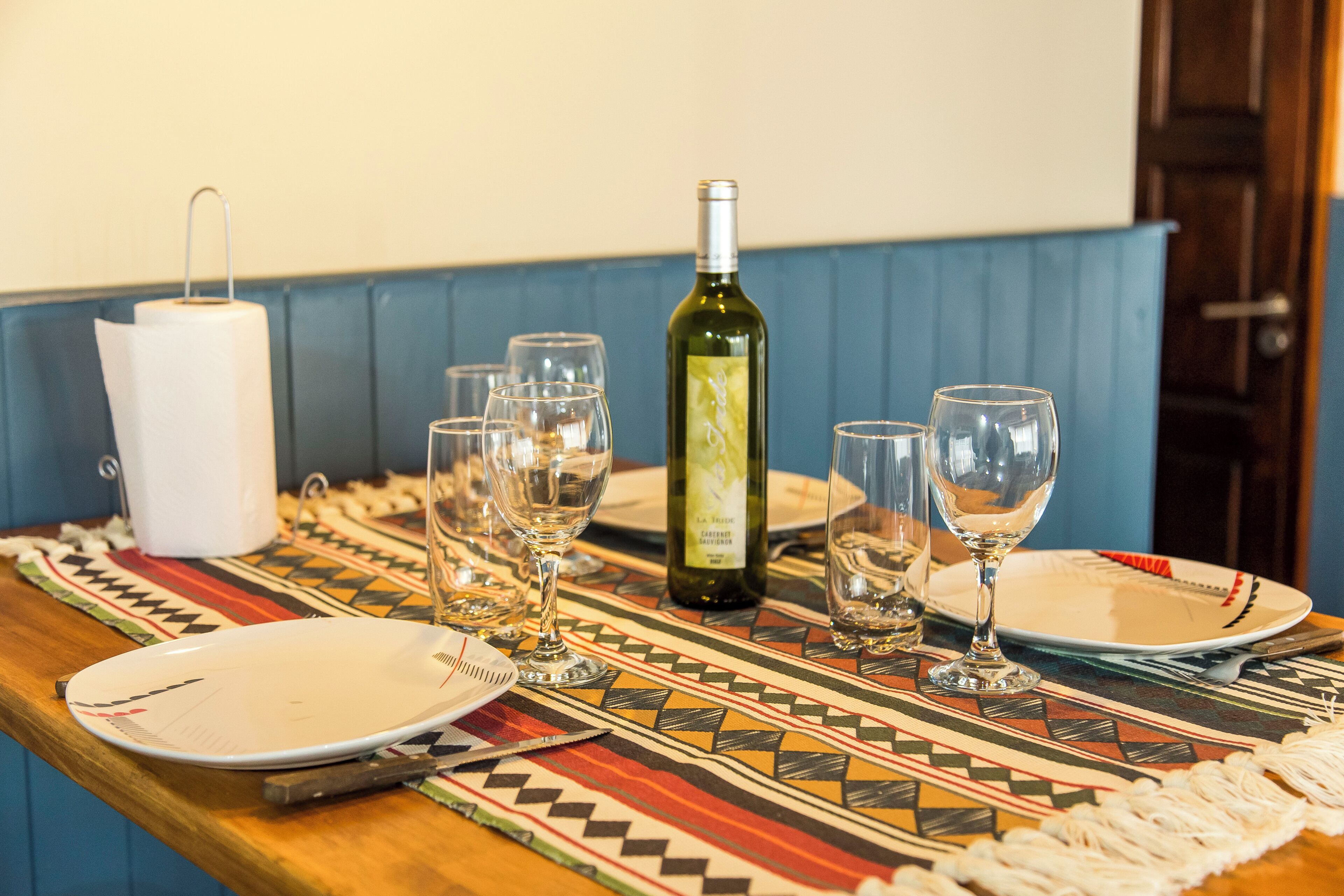 Een eettafel gedekt met borden, glazen en een fles wijn.