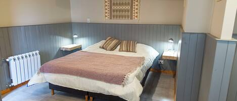 Un dormitorio con cama, lámparas de noche, un radiador y un aplique de pared.
