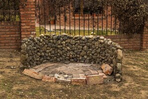 A stone bench with a metal railing in a garden setting.