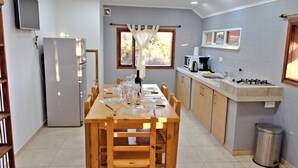 Cozinha com mesa de jantar posta para seis pessoas, geladeira, micro-ondas, cafeteira e pia.