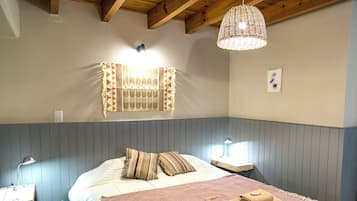 A bedroom with a bed, bedside lamps, a wall-mounted light fixture, and a framed picture.