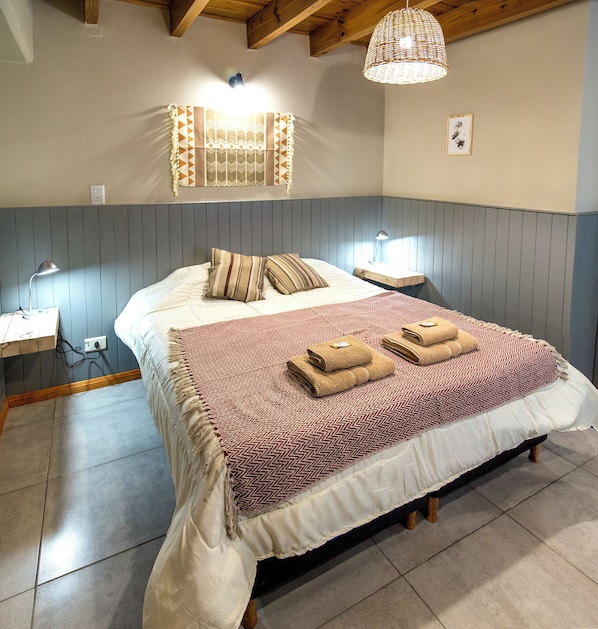 A bedroom with a bed, bedside lamps, a wall-mounted light fixture, and a framed picture.