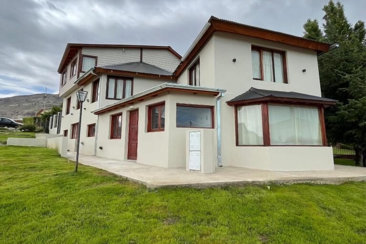 A two-story house with a flat roof, a small attached garage, and a well-maintained lawn.