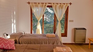 Quarto com cama, luminária de cabeceira, aquecedor e janela com cortinas.