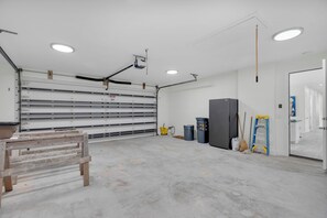 Eine Garage mit großer offener Tür, Werkbank sowie verschiedenen Werkzeugen und Aufbewahrungsbehältern.