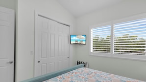 A bedroom with a bed, a television on the wall, a window with blinds, and a door. - Coco Plum Getaway - Dockage -short walk to Coco Plum Beach - Brand New Home! (Marathon)