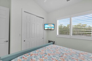 A bedroom with a bed, a television on the wall, a window with blinds, and a door. - Coco Plum Getaway - Dockage -short walk to Coco Plum Beach - Brand New Home! (Marathon)
