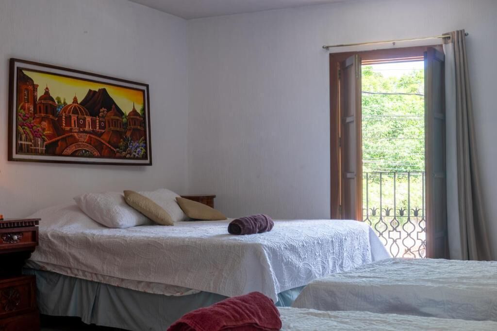 Ein Schlafzimmer mit zwei Betten, einem Bild an der Wand und einem Balkon mit Metallgeländer.