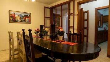 A dining area with a round table, chairs, and a painting on the wall.