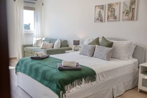 Une chambre à coucher avec un lit, un canapé, une table de chevet et une lampe.