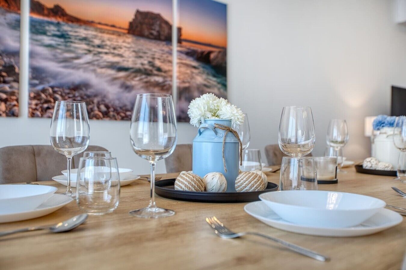 A dining table set with wine glasses, plates, and a decorative centerpiece.