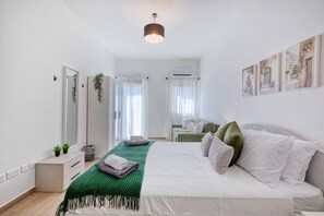 A modern bedroom with a bed, a green throw blanket, and a bedside table.