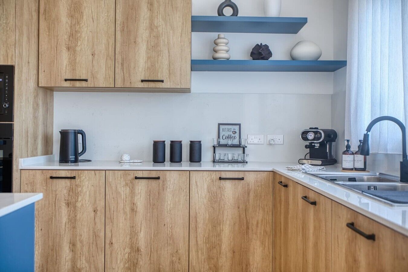 Une cuisine moderne avec des meubles en bois, un coin café et un four encastré.