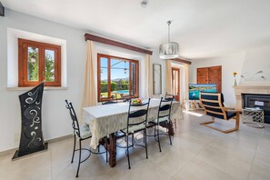 A dining area with a table set for four, a fireplace, and a television. - Pollensa Country Villa for 6 (Pollença)