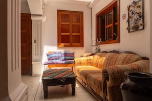 A room with a sofa, a bench, and a window with wooden shutters. - Casa Cielo Antigua - Double Room (Antigua Guatemala)