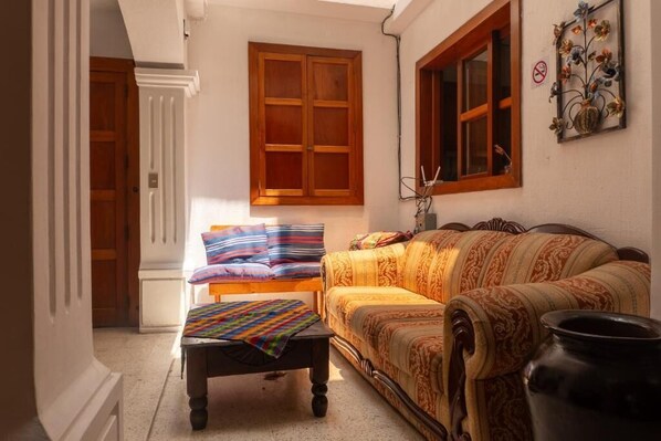 A room with a sofa, a bench, and a window with wooden shutters.