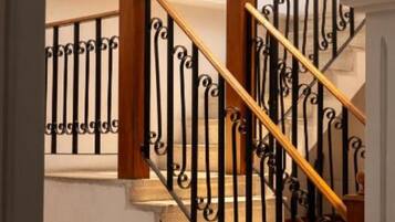 Una escalera con barandilla de madera y balaustrada de hierro forjado negro.