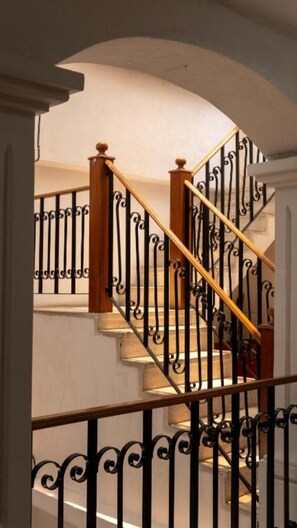 A staircase with a wooden handrail and black wrought iron balusters.
