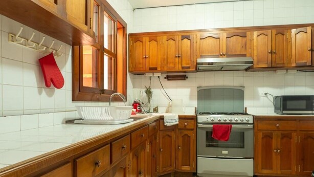 Una cocina con armarios de madera, estufa de acero inoxidable y microondas.
