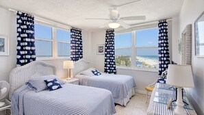 A room with two beds, a ceiling fan, and a view of the beach. - Beachside Paradise - Views, Pool & Sunshine (New Smyrna Beach)