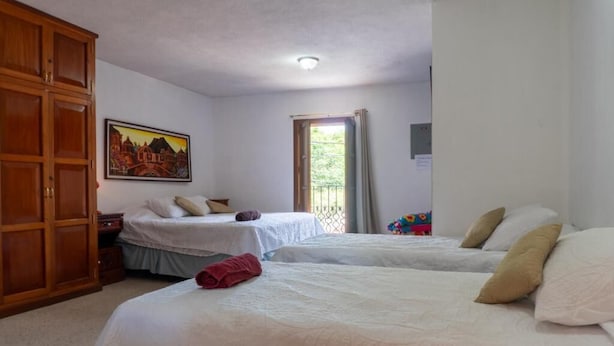Habitación de hotel con dos camas, un armario, un cuadro en la pared y una ventana con cortinas.
