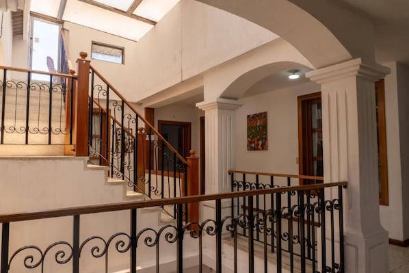 A staircase with ornate black railings and wooden handrails, leading to an upper floor.