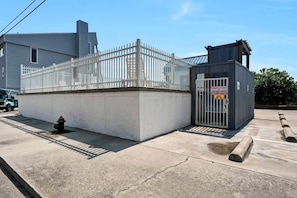 A gated area with a fire hydrant, a metal fence, and a small building with a sign. - Ocean View Oasis | Walk to Carolina Beach! (Carolina Beach)