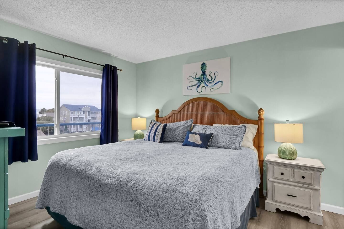 A bedroom with a bed, nightstands, a window with curtains, and a wall painting.