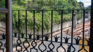 A view through a metal gate with a decorative pattern, leading to a street with a concrete wall and a tiled roof. - Casa Cielo Antigua - Double Room with Private Bathroom (Antigua Guatemala)