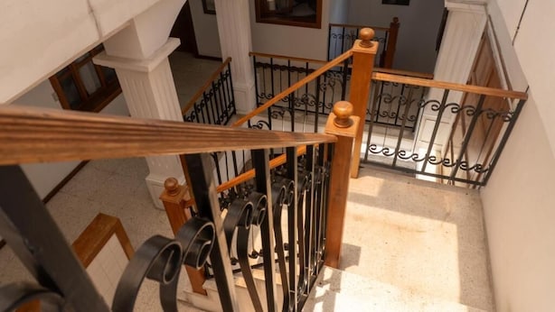 A staircase with a wooden handrail and black metal balusters, leading to an upper floor. - Casa Cielo Antigua - Double Room with Private Bathroom (Antigua Guatemala)