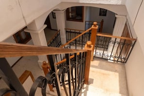 A staircase with a wooden handrail and black metal balusters, leading to an upper floor.