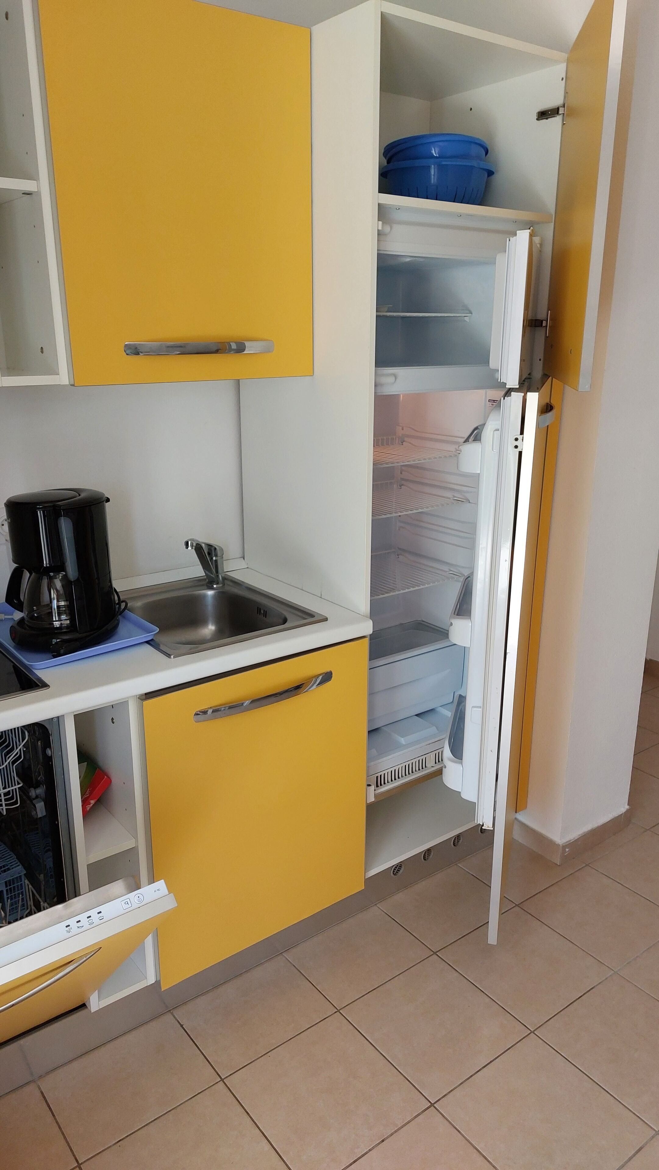 A compact kitchen with a coffee maker, a sink, and a refrigerator with shelves.