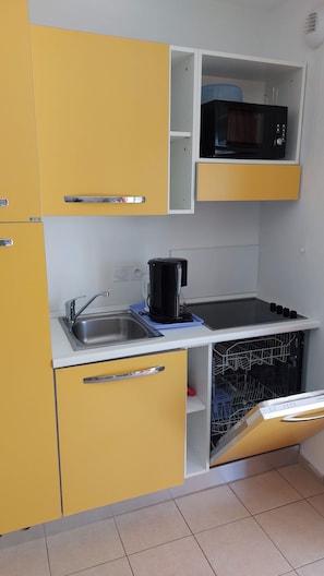 A compact kitchen with a microwave, coffee maker, and dishwasher.