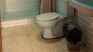 Et badeværelse med bruser, toilet, håndvask og håndklædetørrestativ.
