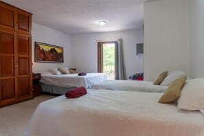 A hotel room with two beds, a wardrobe, a painting on the wall, and a window with curtains. - Casa Cielo Antigua - Deluxe Double Room (Antigua Guatemala)