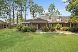 A two-story brick house with a front porch, a covered entryway, and a well-maintained lawn.