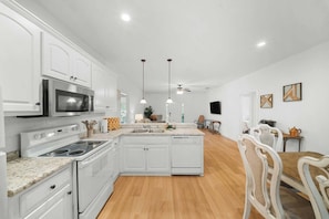 Una cocina moderna con armarios blancos, electrodomésticos de acero inoxidable y una isla central.