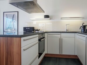 A modern kitchen with white cabinets, a black countertop, and stainless steel appliances. - House Zur Mole, Apartment 20 "meerkieker" (Grossenbrode)