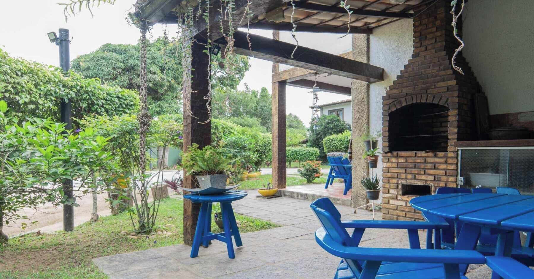 Une terrasse extérieure avec des tables et des chaises bleues, un four en briques et des plantes en pot.