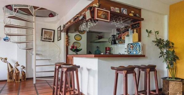 Eine Küche mit Bar, Holzstühlen und einer Wendeltreppe.