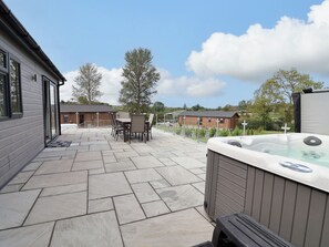 Eine Terrassenanlage mit Whirlpool, Gartenmöbeln und Blick auf die umliegende Landschaft.