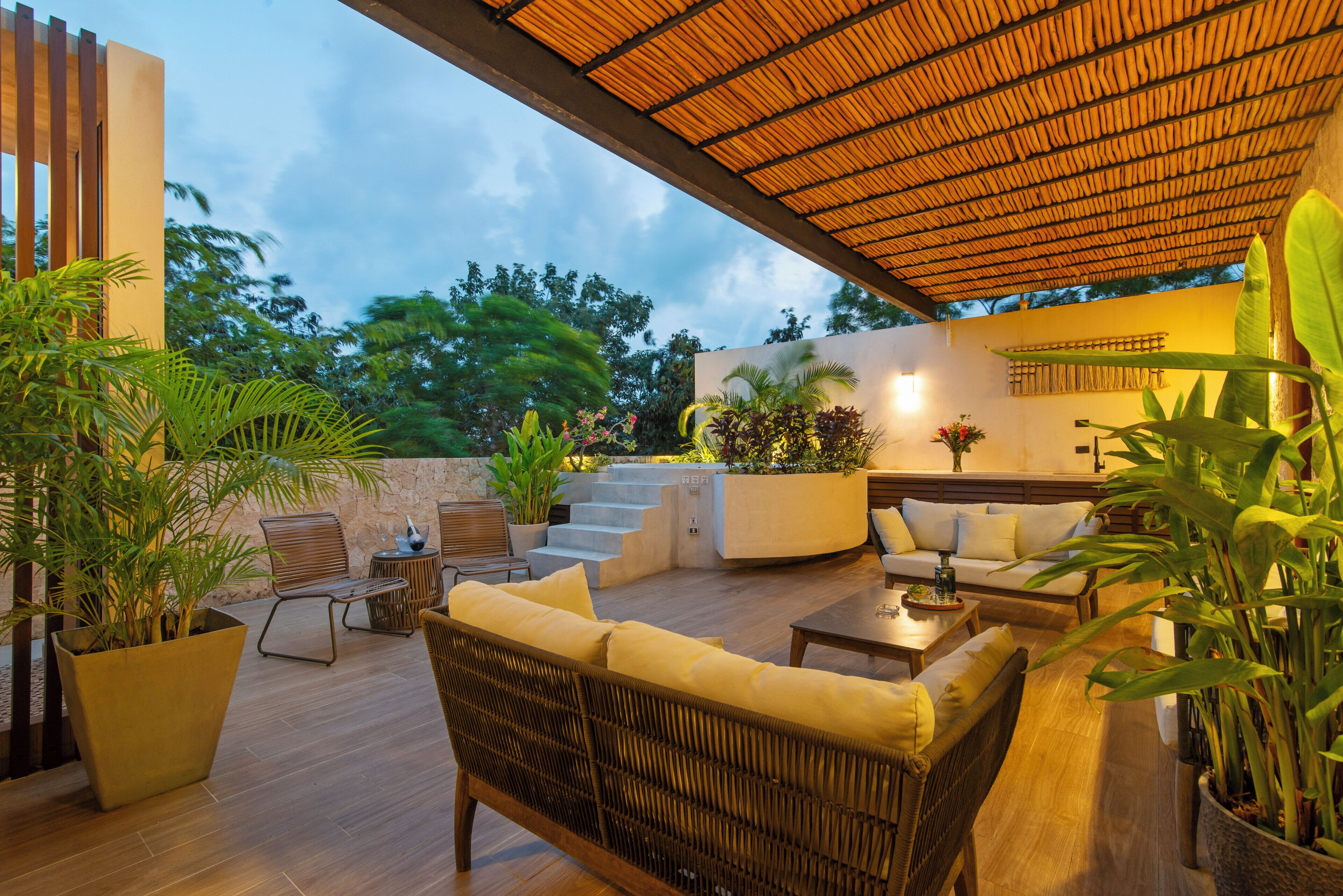 Un patio al aire libre con muebles de mimbre, una pared de piedra y un techo de madera.