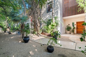 A courtyard with a gravel path, potted plants, and a building with a wooden door. - 4BR Luxury Villa w/ Pool & Heated Jacuzzi +Staff @ BlueDeerTulum (Tulum)